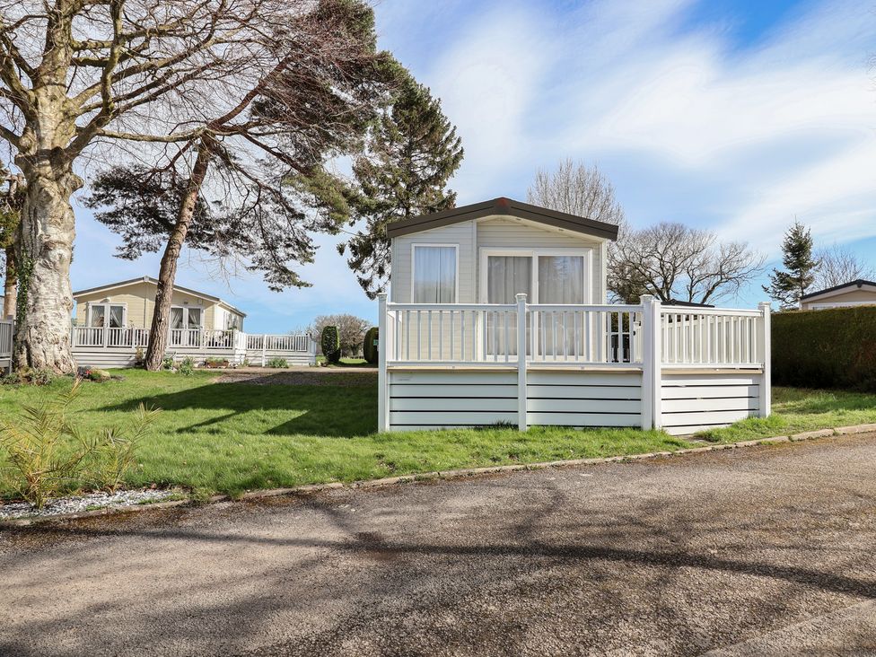 A caravan with a deck at Woodlands Hall Caravan Park near Ruthin