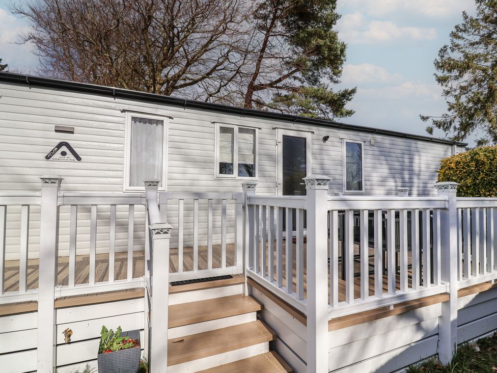 A caravan with a deck and steps at Woodlands Hall Caravan Park near Ruthin