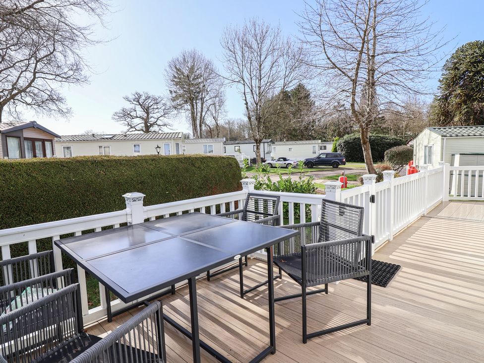 An outdoor seating area with a table and chairs at Caravan Woodlands Hall Caravan Park near Ruthin