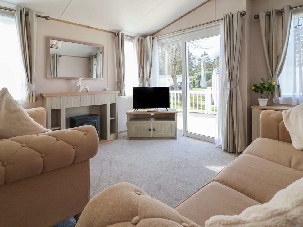 A living room with a television and a mirror at Caravan near Woodlands Hall Caravan Park near Ruthin