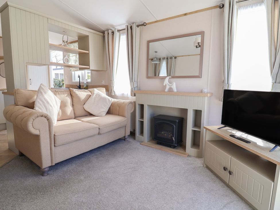 A living room with a sofa and television at Caravan in Woodlands Hall Caravan Park near Ruthin