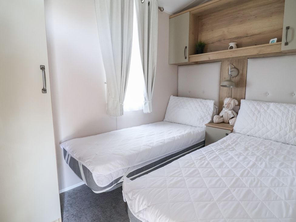 A bedroom with two beds and a bedside table at Caravan Woodlands Hall Caravan Park near Ruthin