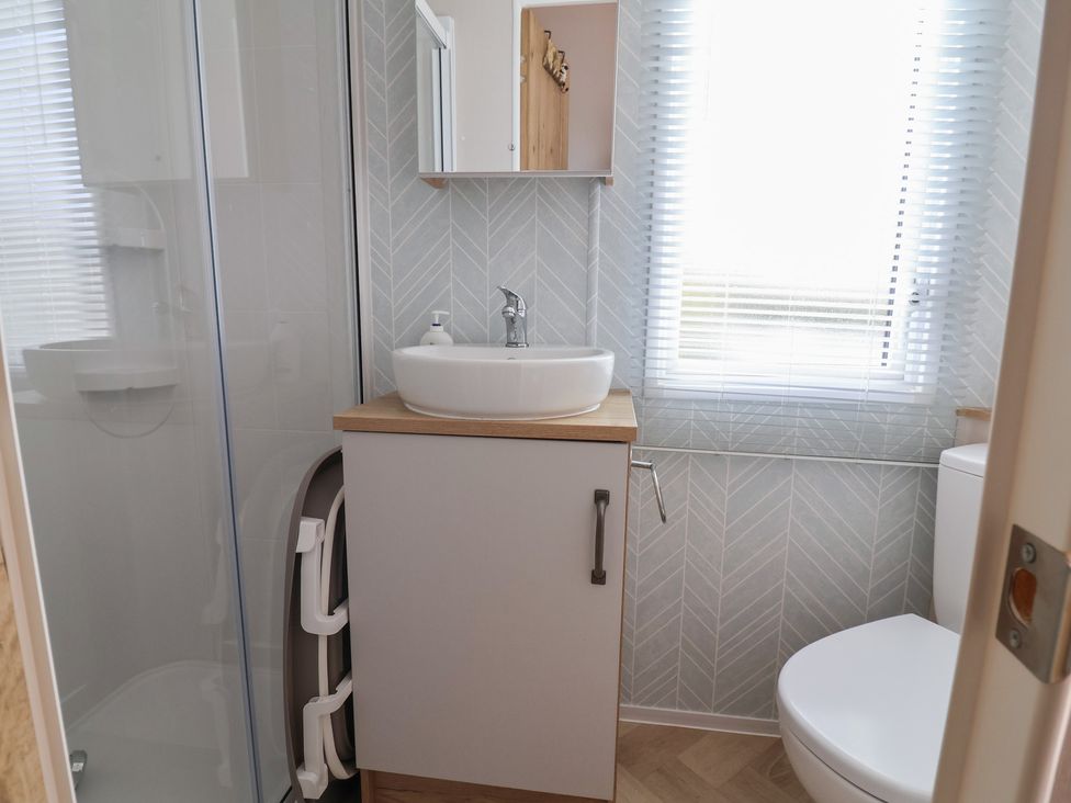 A bathroom with a shower, sink, and toilet at Caravan in Woodlands Hall Caravan Park near Ruthin