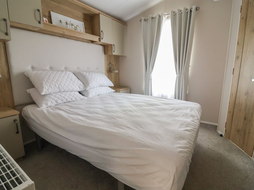 A bedroom with a bed and shelf at Caravan in Woodlands Hall Caravan Park near Ruthin
