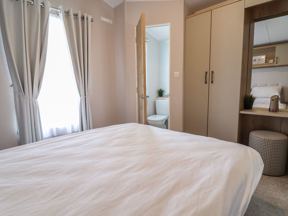 A bedroom with a bed and an adjoining bathroom at Caravan Woodlands Hall Caravan Park near Ruthin