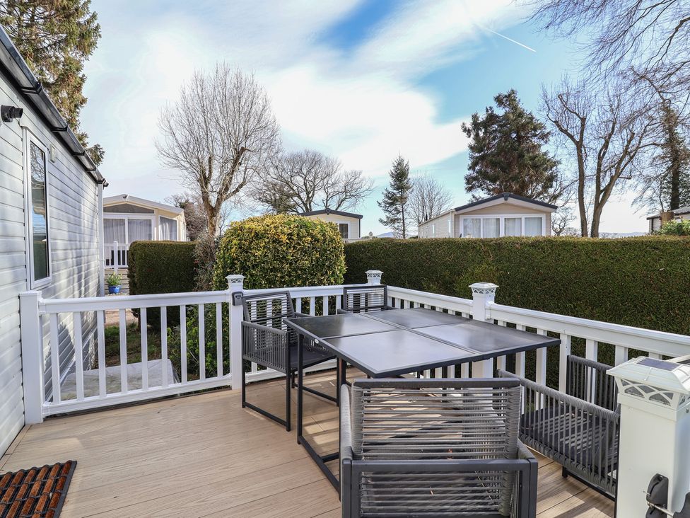 An outdoor seating area with a table and chairs at Caravan Woodlands Hall Caravan Park near Ruthin