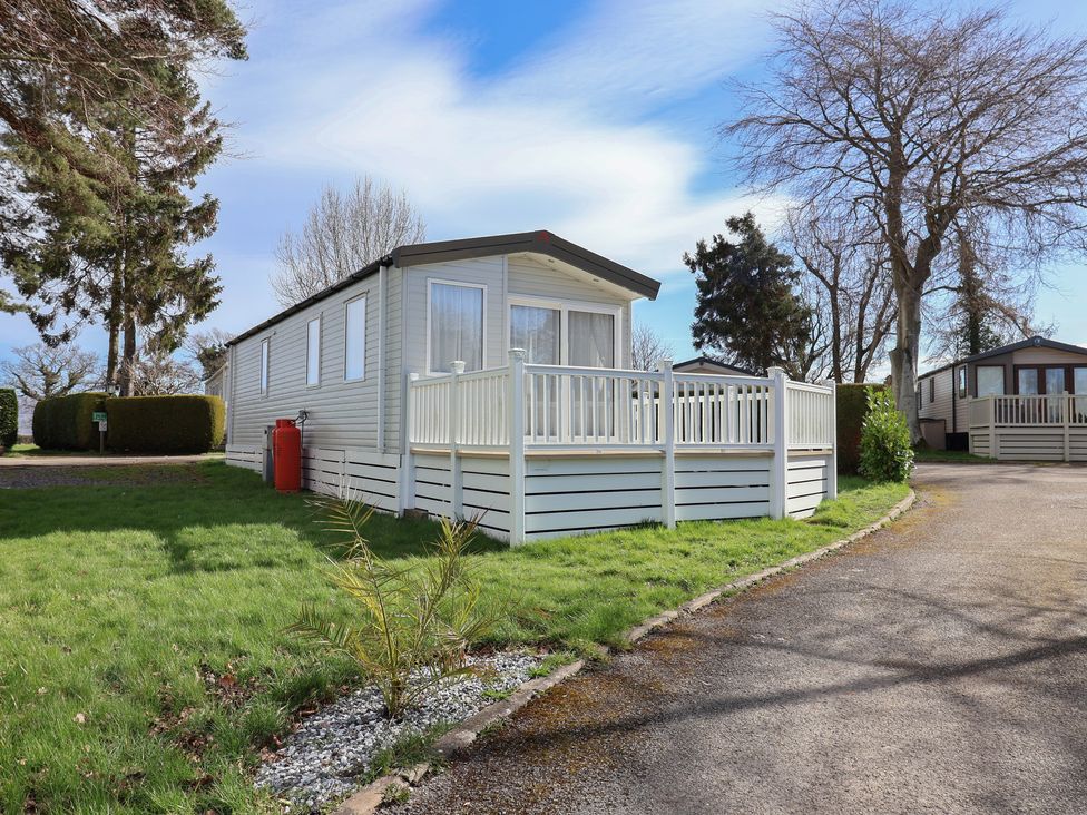A caravan with a deck at Woodlands Hall Caravan Park near Ruthin
