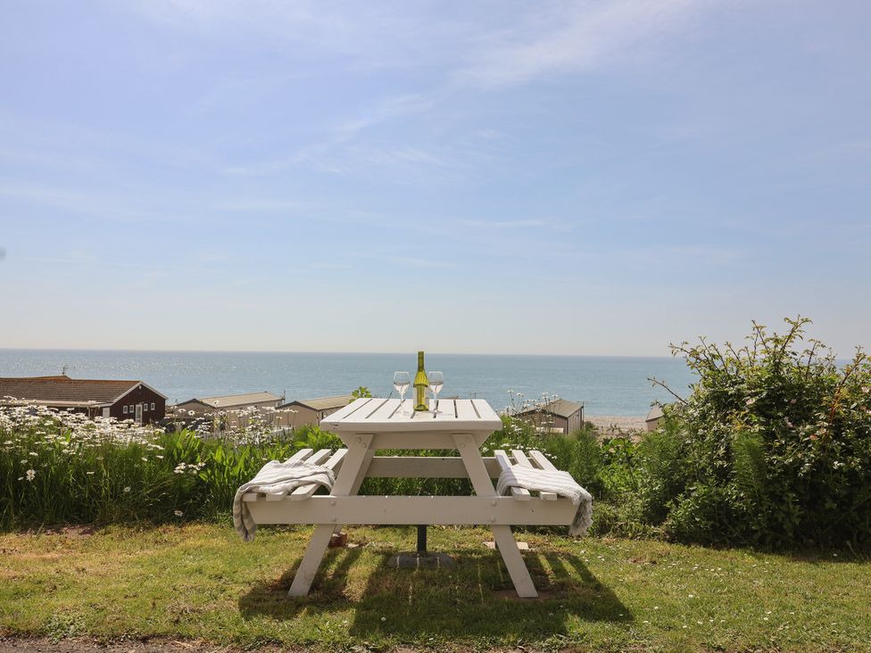 A table with a bottle and glasses overlooking the sea at Salt & Stone Lyme Regis