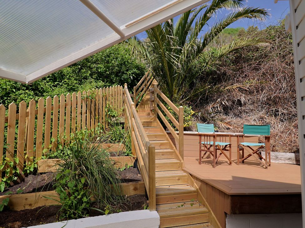 A wooden deck area with chairs and stairs at Salt & Stone Lyme Regis