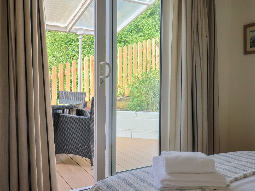 A bedroom with a door leading to an outdoor seating area at Salt & Stone in Lyme Regis