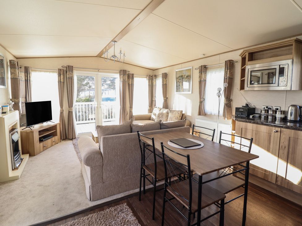 A living room with a television and dining table at 23 Gull Court in Porthmadog