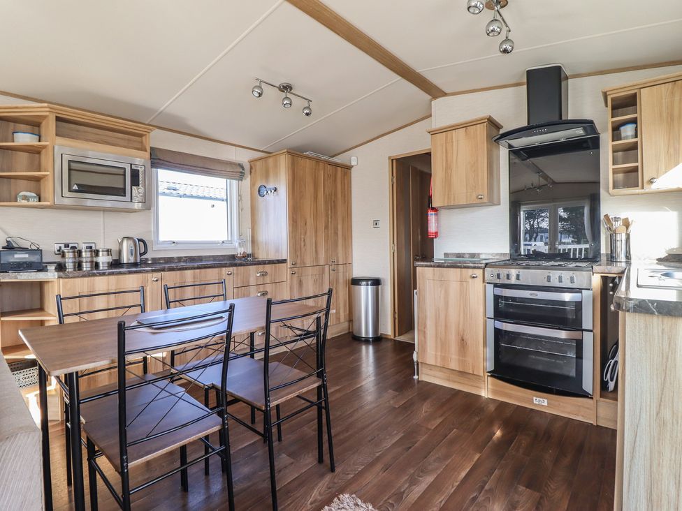 A kitchen with appliances and a dining table at 23 Gull Court Porthmadog