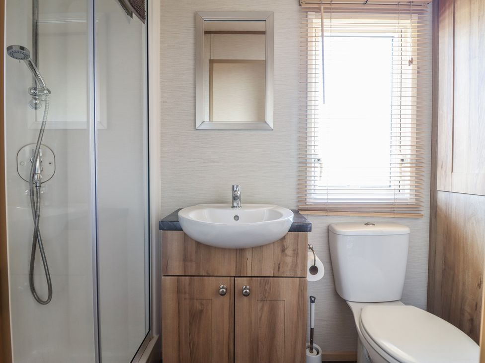A bathroom with a shower, sink, and toilet at 23 Gull Court in Porthmadog