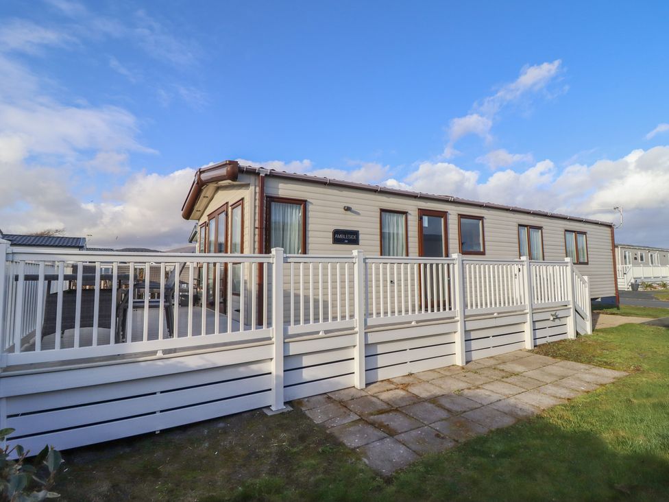 A mobile home with a deck and fence at 23 Gull Court in Porthmadog