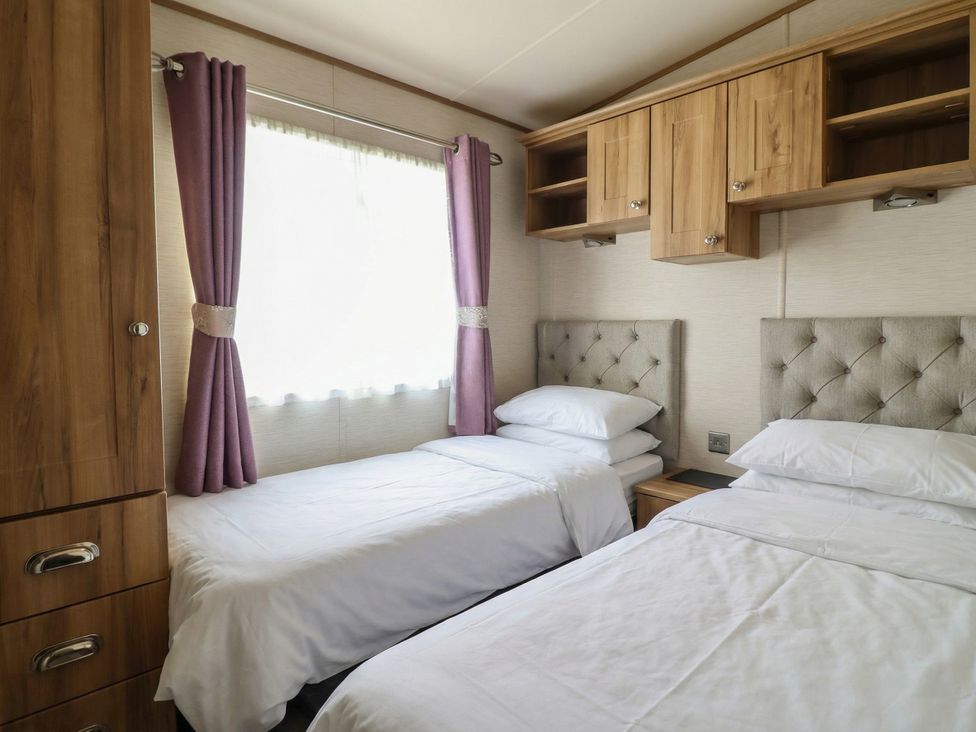 A bedroom with two beds and a window at 23 Gull Court in Porthmadog