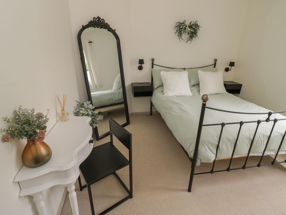 A bedroom with a bed, mirror, and a chair at 3 Swedish House in Walgrave
