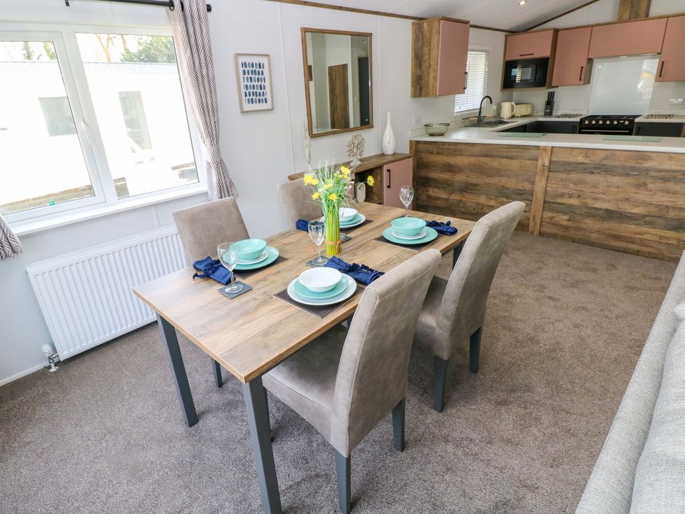 A dining room with a table set and kitchen area at Dukes Meadow in Carmarthen