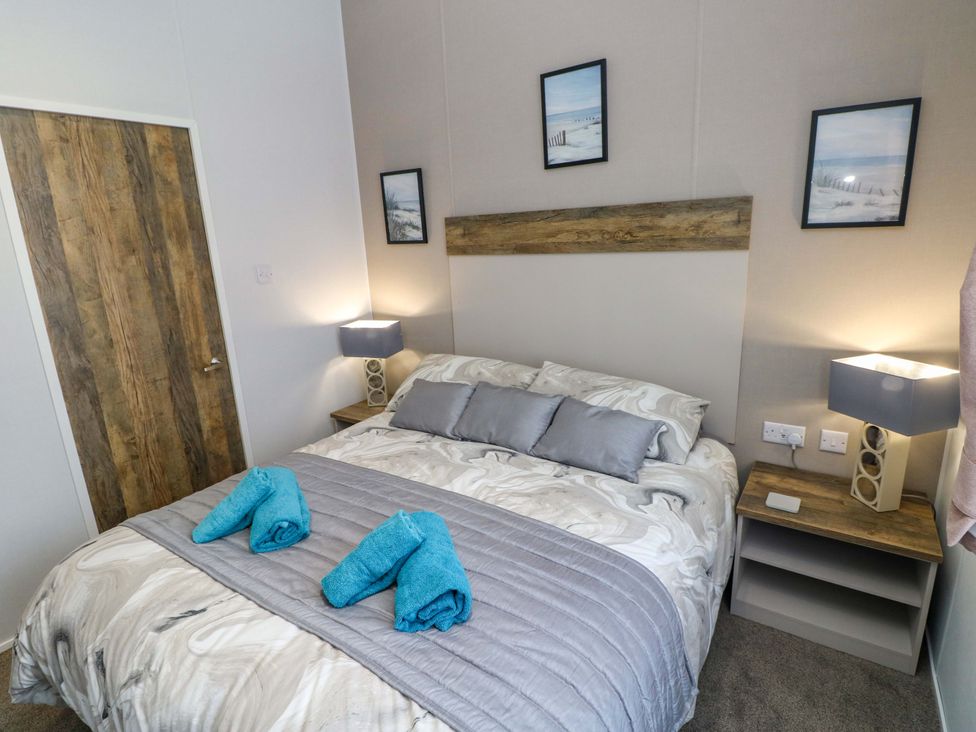 A bedroom with a bed and bedside tables at Dukes Meadow, Carmarthen