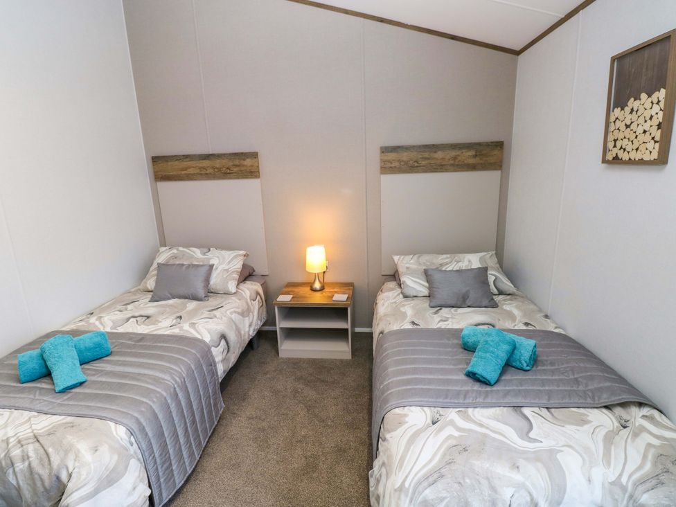 A bedroom with two beds and a bedside table at Dukes Meadow, Carmarthen