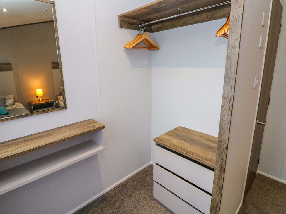A bedroom with a wardrobe area and a mirror at Dukes Meadow in Carmarthen
