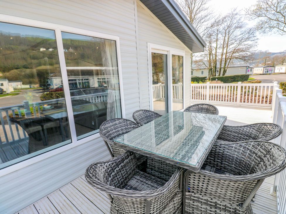 A dining area with a table and chairs on a deck at Dukes Meadow in Carmarthen