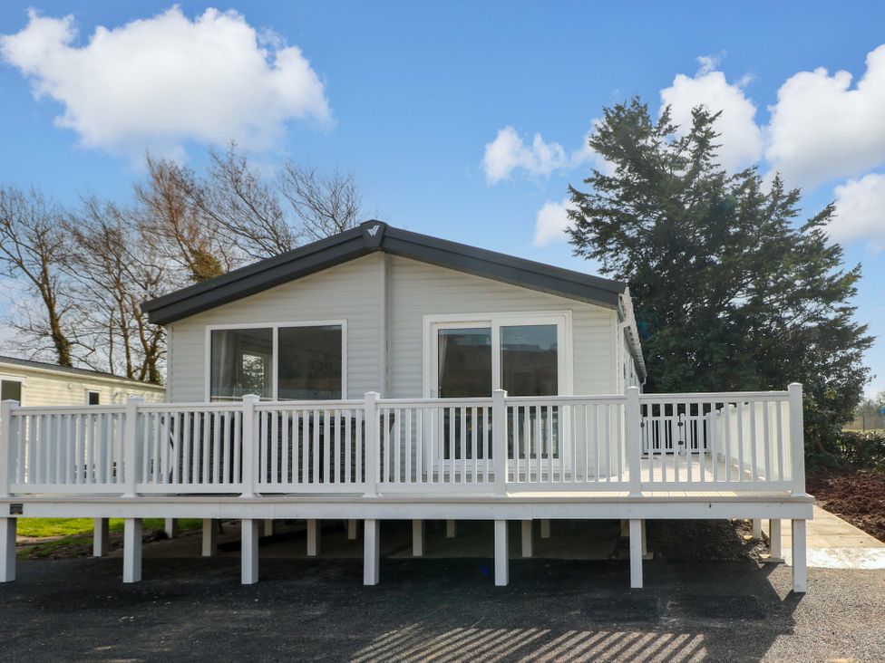 A house with a deck and trees at Dukes Meadow Carmarthen