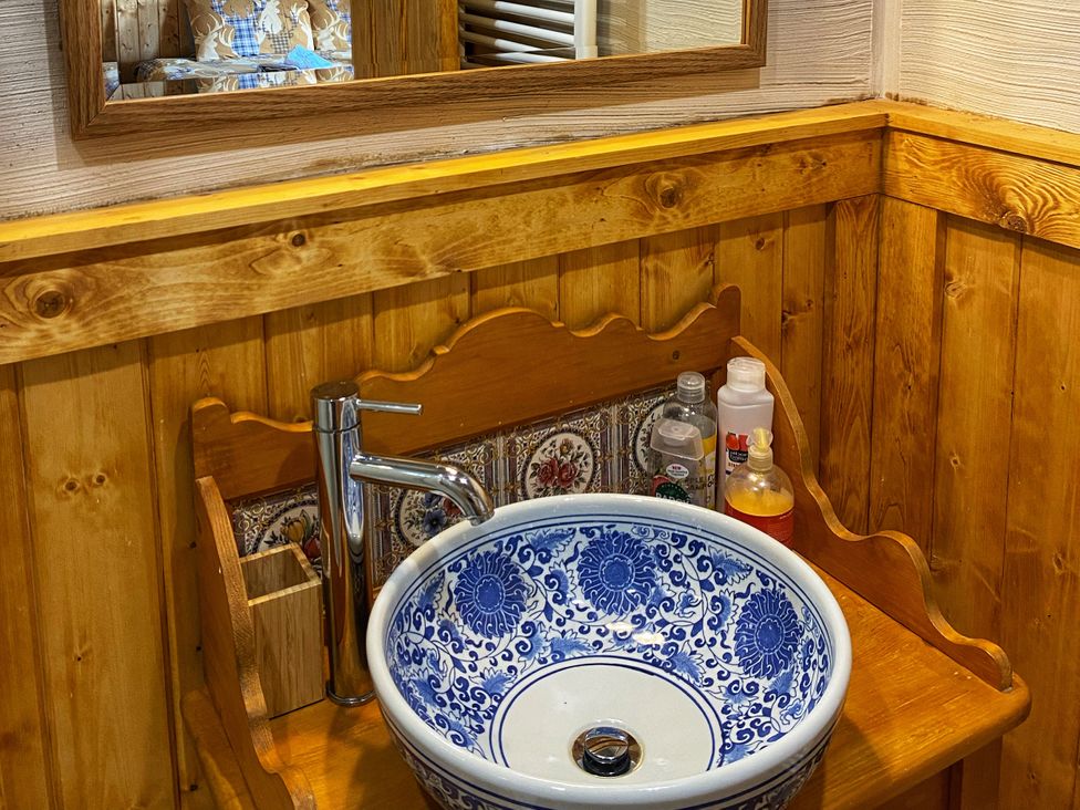A wash basin with a faucet and mirror in a wooden bathroom at No. 7 Enniskillen
