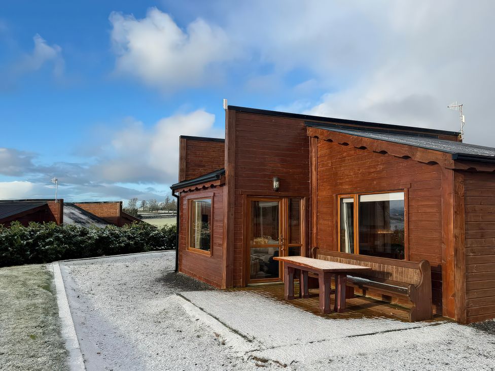 A wooden cabin with a bench outside at No. 7 Enniskillen