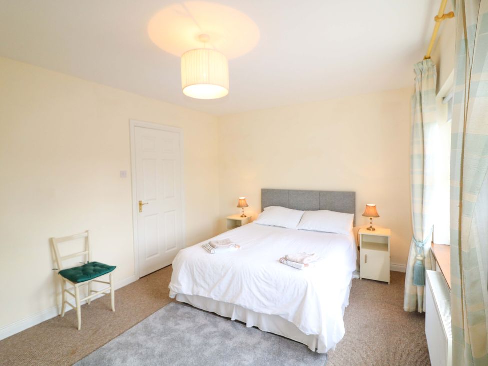 A bedroom with a bed and chairs at Lugdine Lodge in Glengarriff