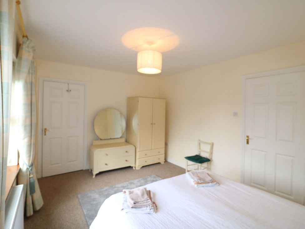 A bedroom with a bed and dresser at Lugdine Lodge in Glengarriff