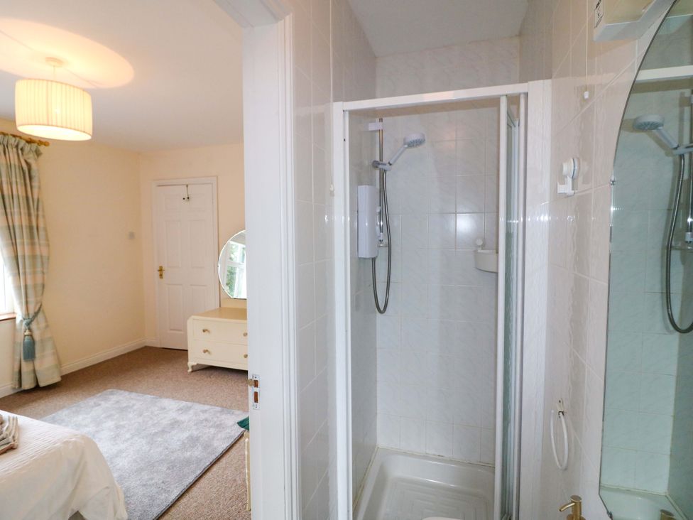 A bathroom with a shower and mirror at Lugdine Lodge in Glengarriff