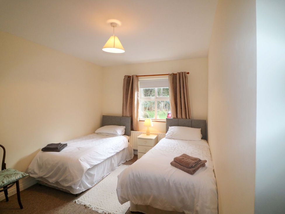 A bedroom with two single beds and a bedside table at Lugdine Lodge, Glengarriff