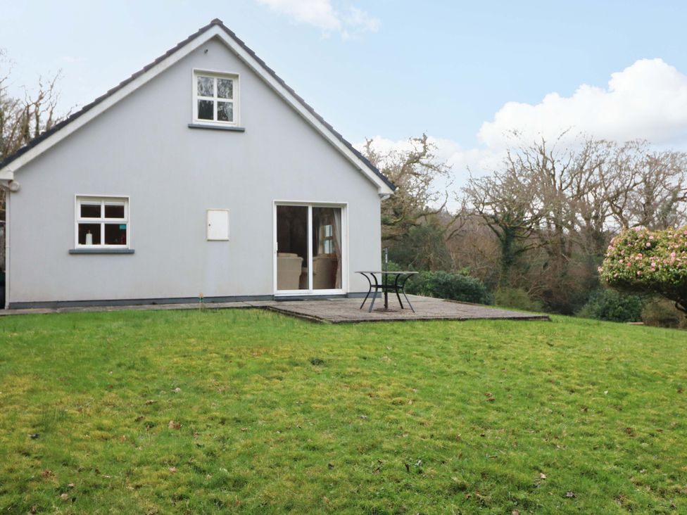 A house with a patio and table in the garden at Lugdine Lodge Glengarriff