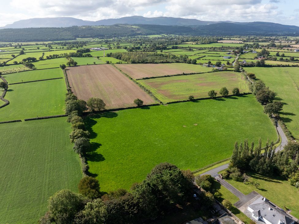 An aerial view of green and brown fields with trees and a road at Ballyneill Farmhouse in Carrick-On-Suir, County Tipperary