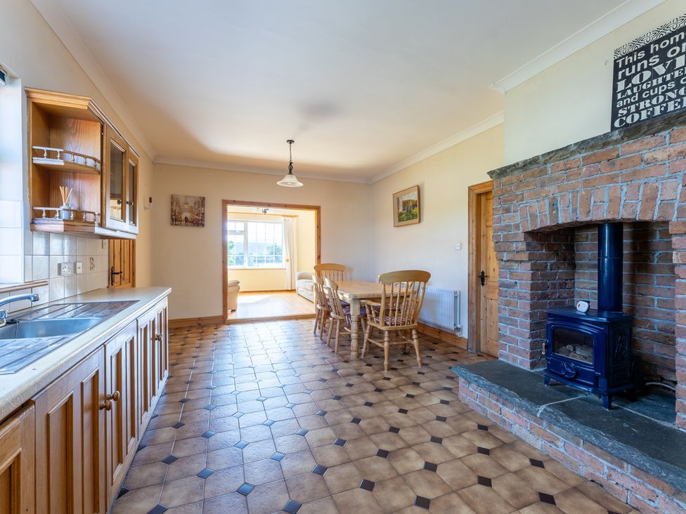A kitchen with a dining area and wood stove at Ballyneill Farmhouse, Carrick-On-Suir, County Tipperary