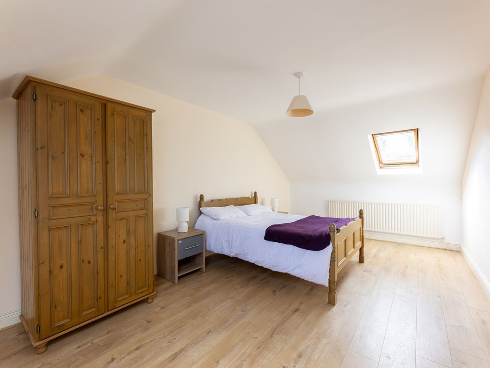 A bedroom with a bed and a wardrobe at Ballyneill Farmhouse, Carrick-On-Suir, County Tipperary