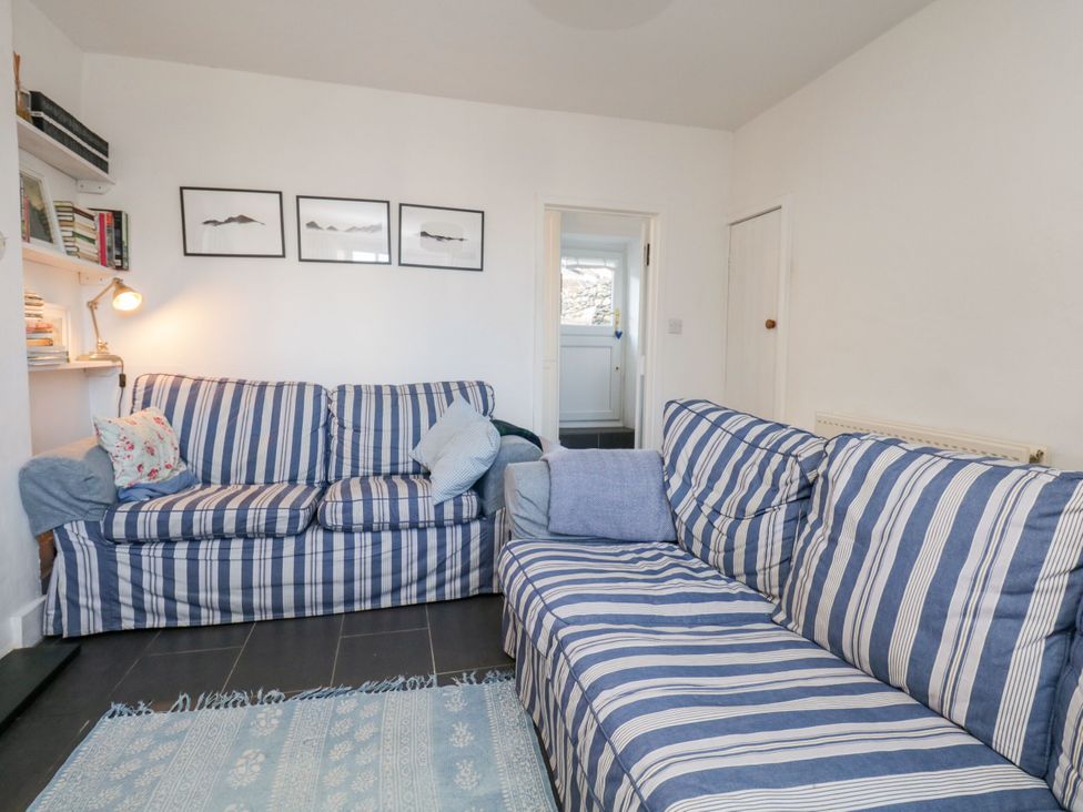 A living room with sofas and a bookshelf at Burnside Cottage in Grange-Over-Sands
