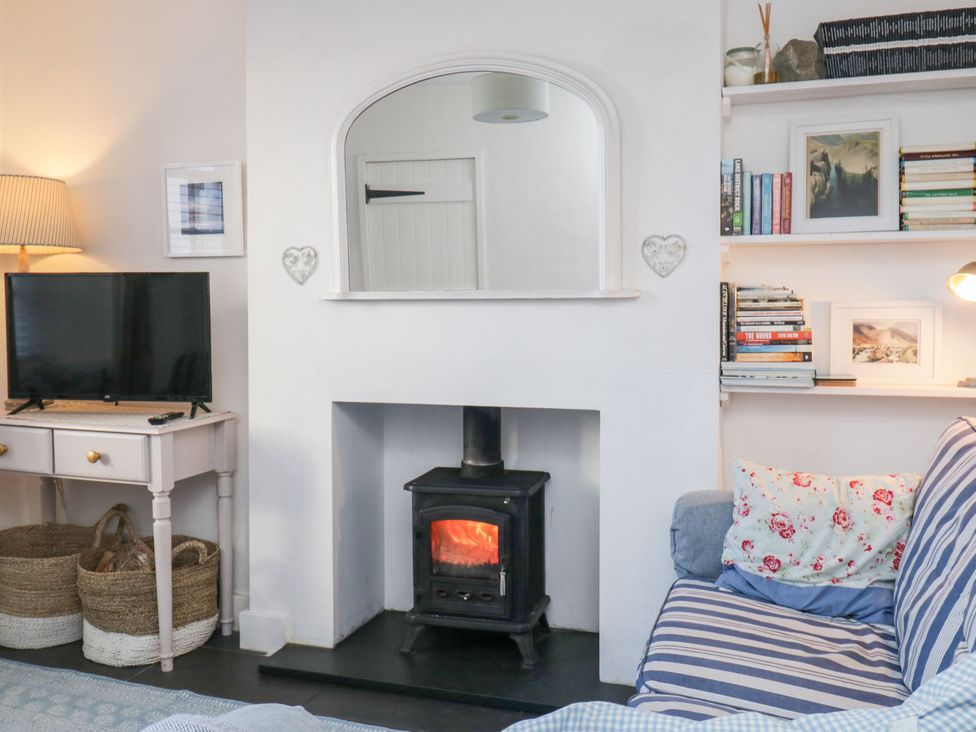 A living room with a fireplace and television at Burnside Cottage in Grange-Over-Sands