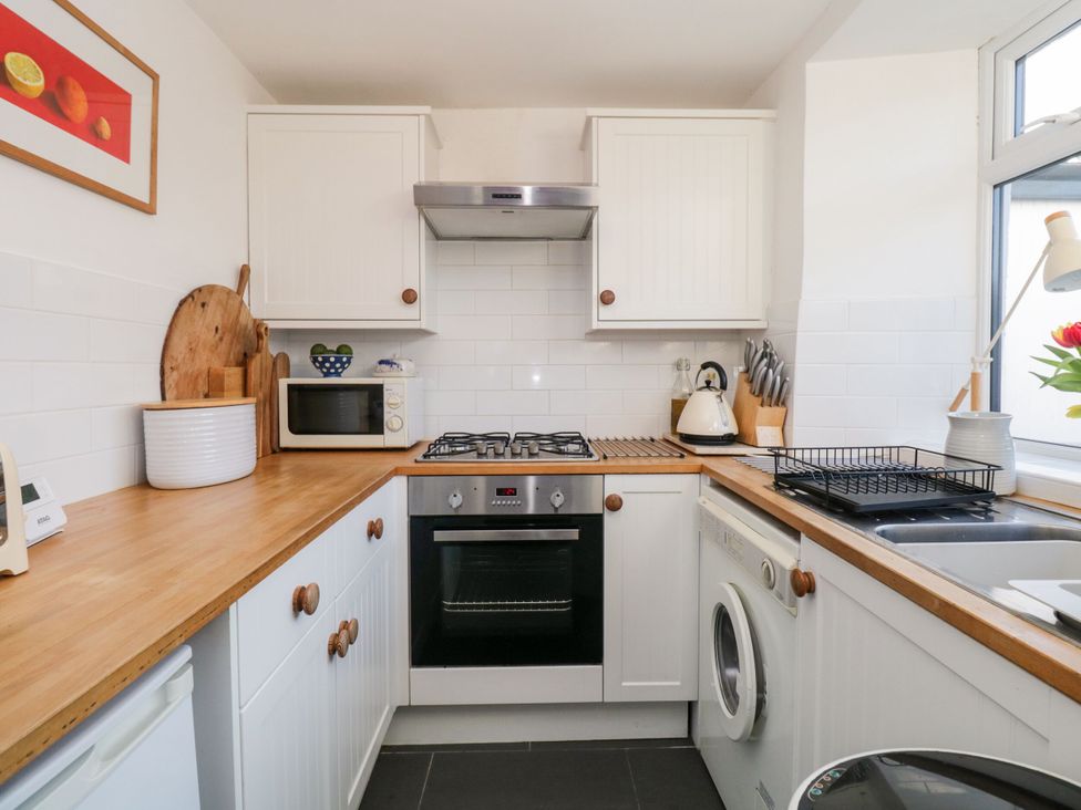 A kitchen with stove, oven, sink, and washing machine at Burnside Cottage in Grange-Over-Sands