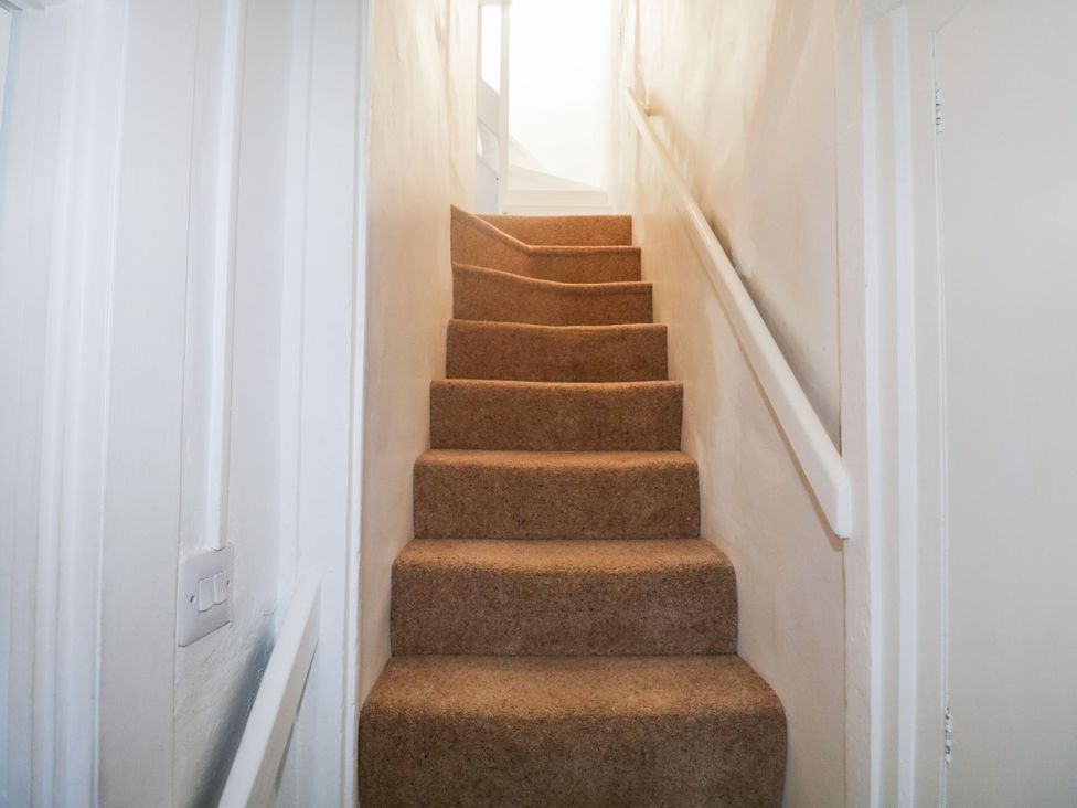A staircase with carpet steps and a handrail at Burnside Cottage Grange-Over-Sands