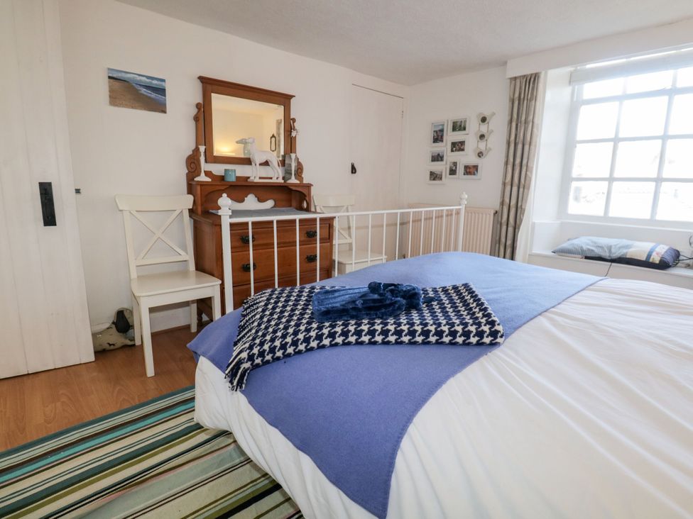 A bedroom with a bed, mirror and dresser at Burnside Cottage in Grange-Over-Sands