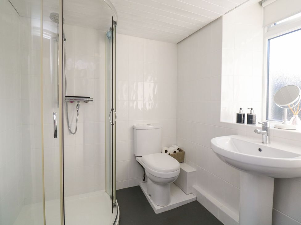 A bathroom with a shower, toilet, and sink at Burnside Cottage, Grange-Over-Sands
