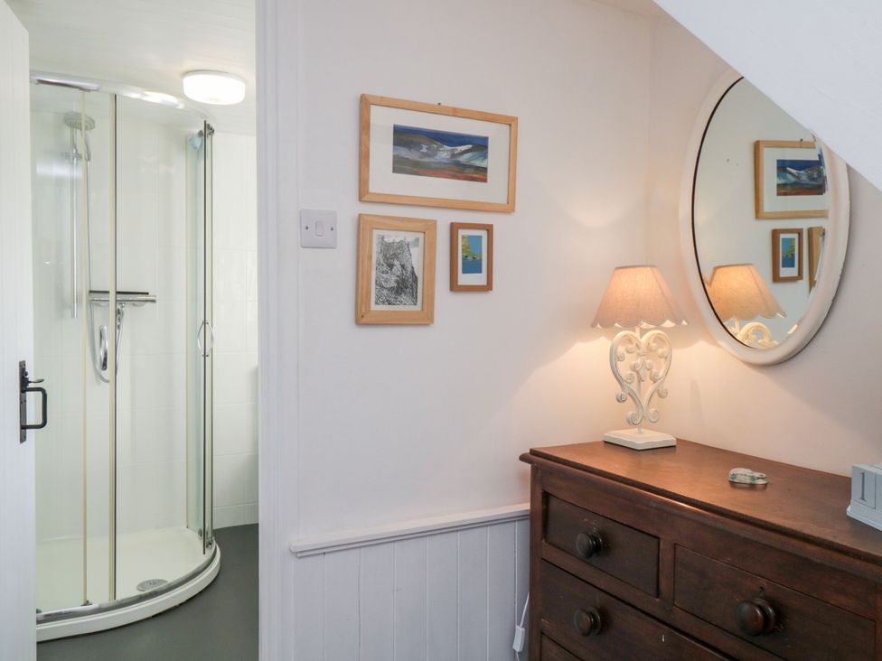A bathroom with a shower, dresser and wall art at Burnside Cottage in Grange-Over-Sands