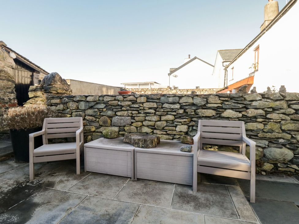 A seating area with chairs and a stone wall at Burnside Cottage in Grange-Over-Sands