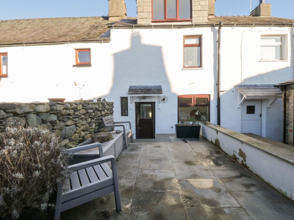 An outdoor space with a stone wall and seating at Burnside Cottage in Grange-Over-Sands