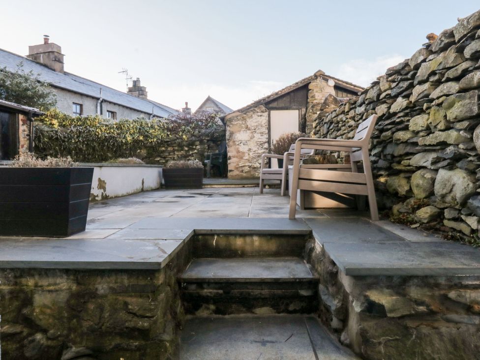 A garden with a stone wall and paved area at Burnside Cottage in Grange-Over-Sands