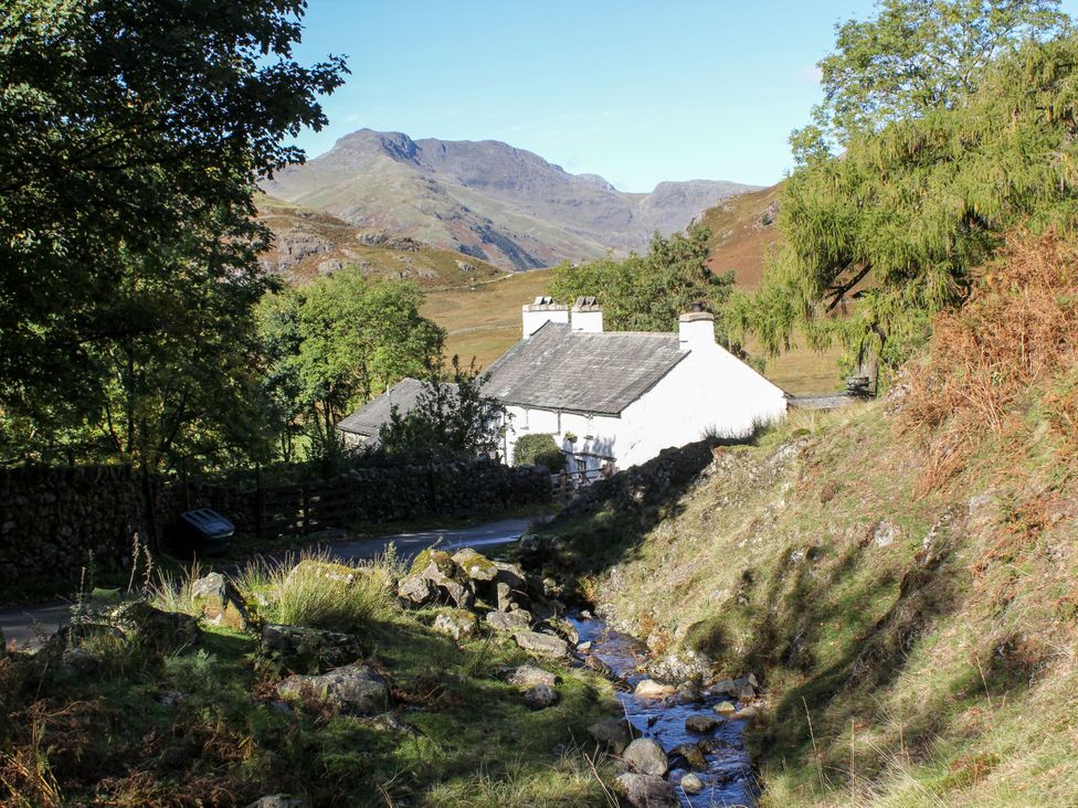 A cottage near a stream surrounded by trees at Burnside Cottage in Grange-Over-Sands