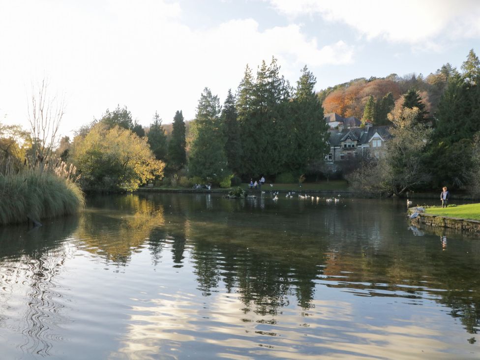 A view of a pond with trees and a building in the background at Burnside Cottage Grange-Over-Sands