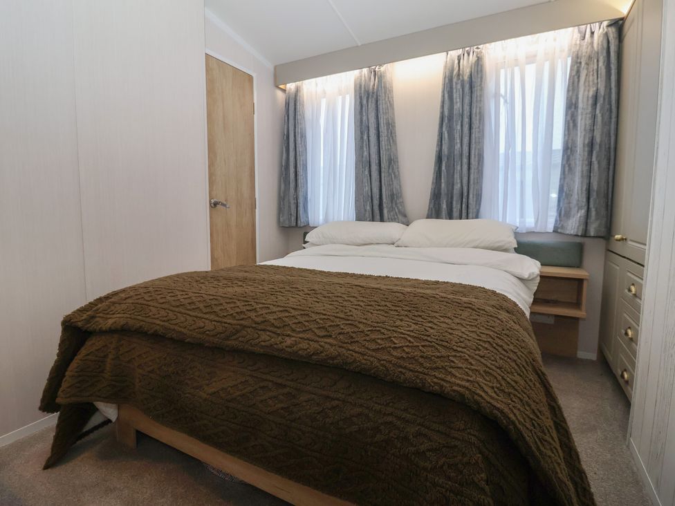 A bedroom with a bed and large window at Lodge 22, Moselle Malton