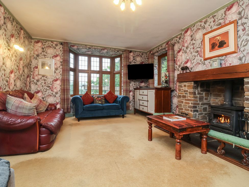 A living room with sofas, a coffee table, and a fireplace at West Down Country House in South Molton